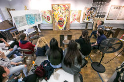 Students sitting around a work of art as part of a critique